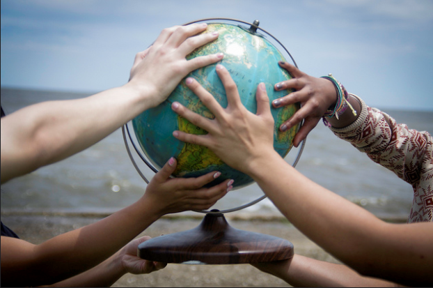 diverse hands on globe on beach