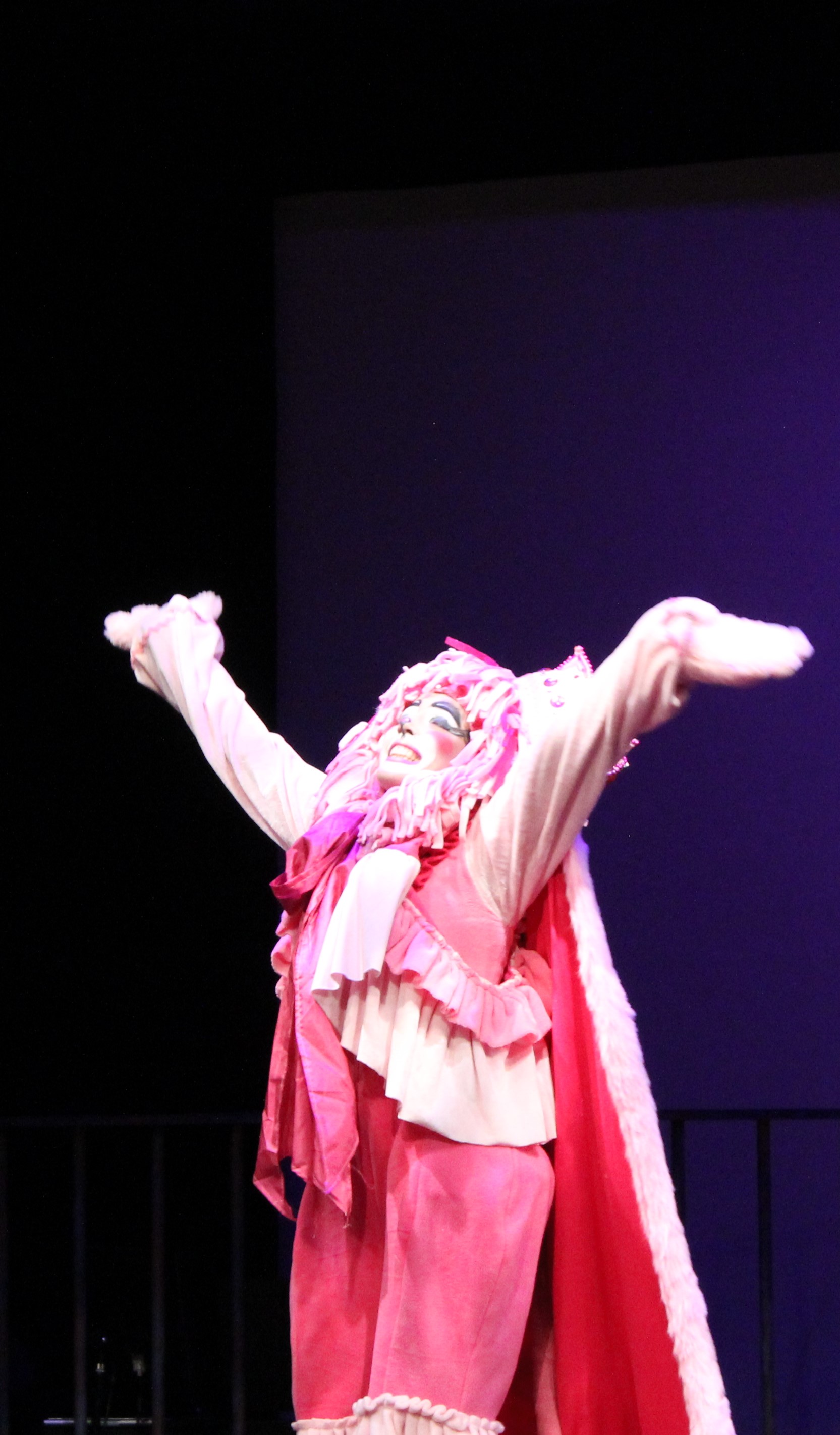person in pink lion costume with arms in the air and eyes closed