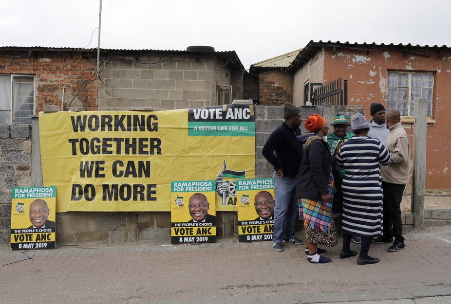 South Africans discussing election beside election posters